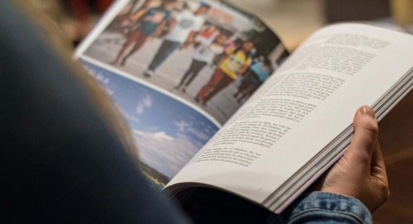 Manos sosteniendo una revista abierta sobre las rodillas